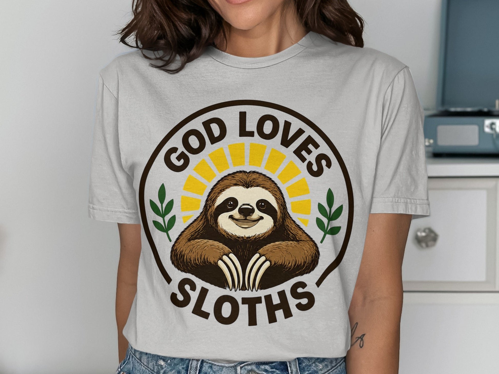 Brown t-shirt with a smiling sloth graphic and "God Loves Sloths" text.