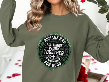 Green crewneck sweatshirt with Romans 8:28 text in a circular design.
