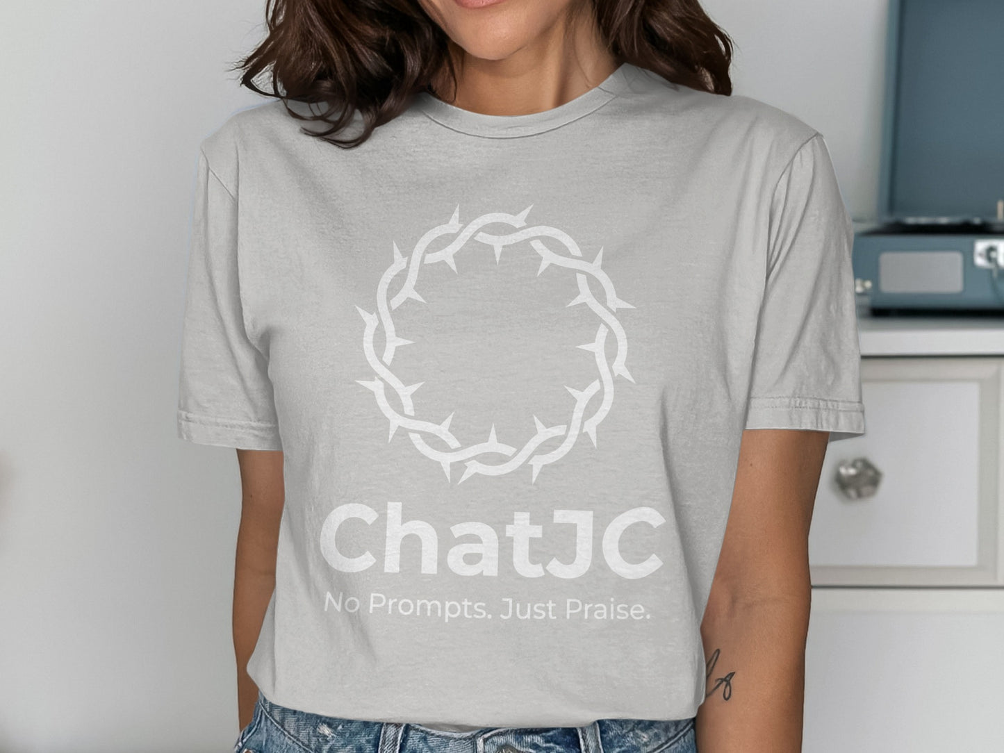 Light gray t-shirt with white thorny crown and "ChatJC No Prompts. Just Praise." text.
