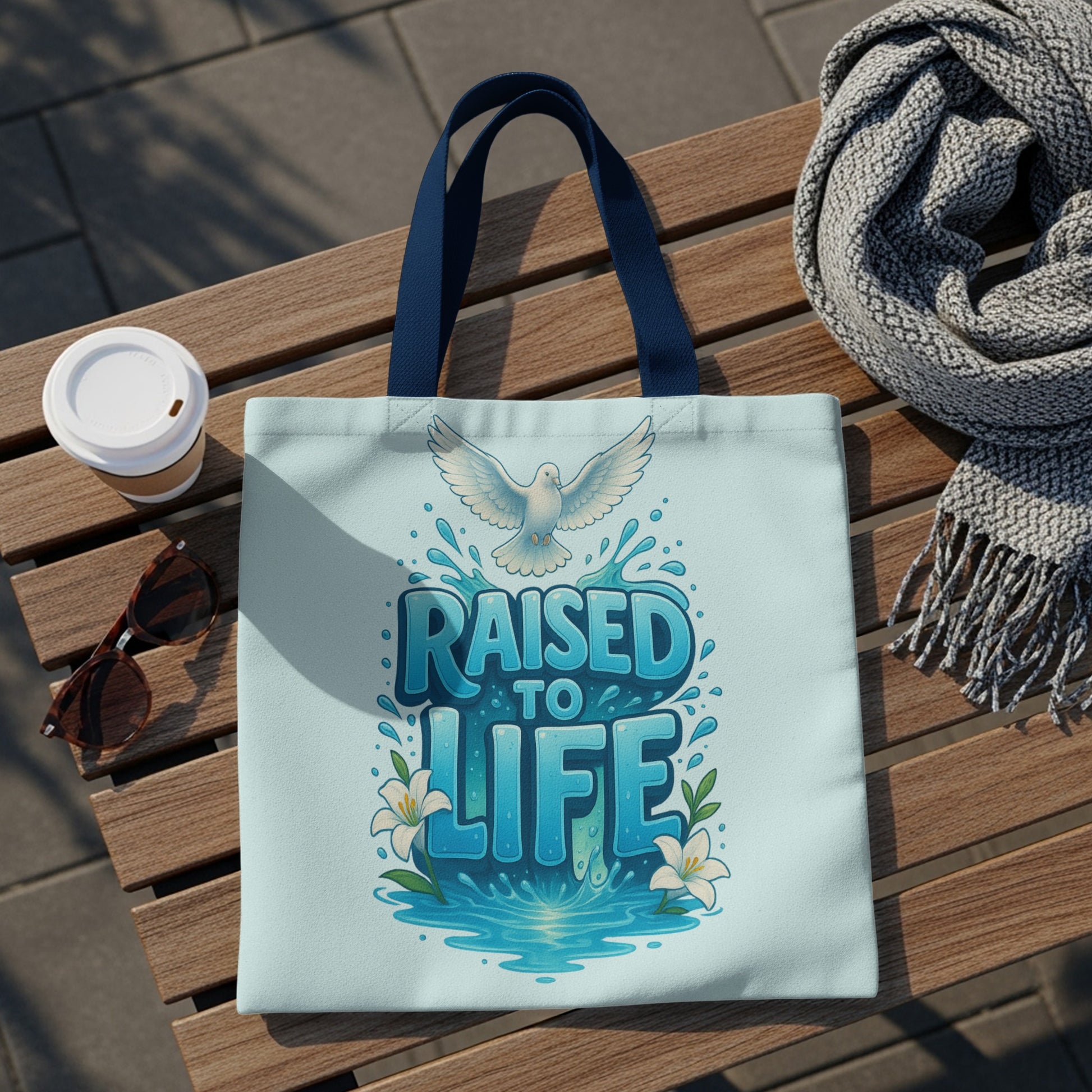 Tote bag with "RAISED TO LIFE" text, dove, water splashes, and lilies.
