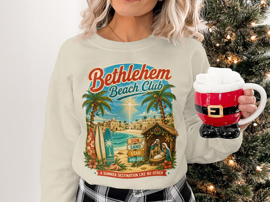 Bethlehem Beach Club sweatshirt with nativity scene, palm trees, and surfboards.